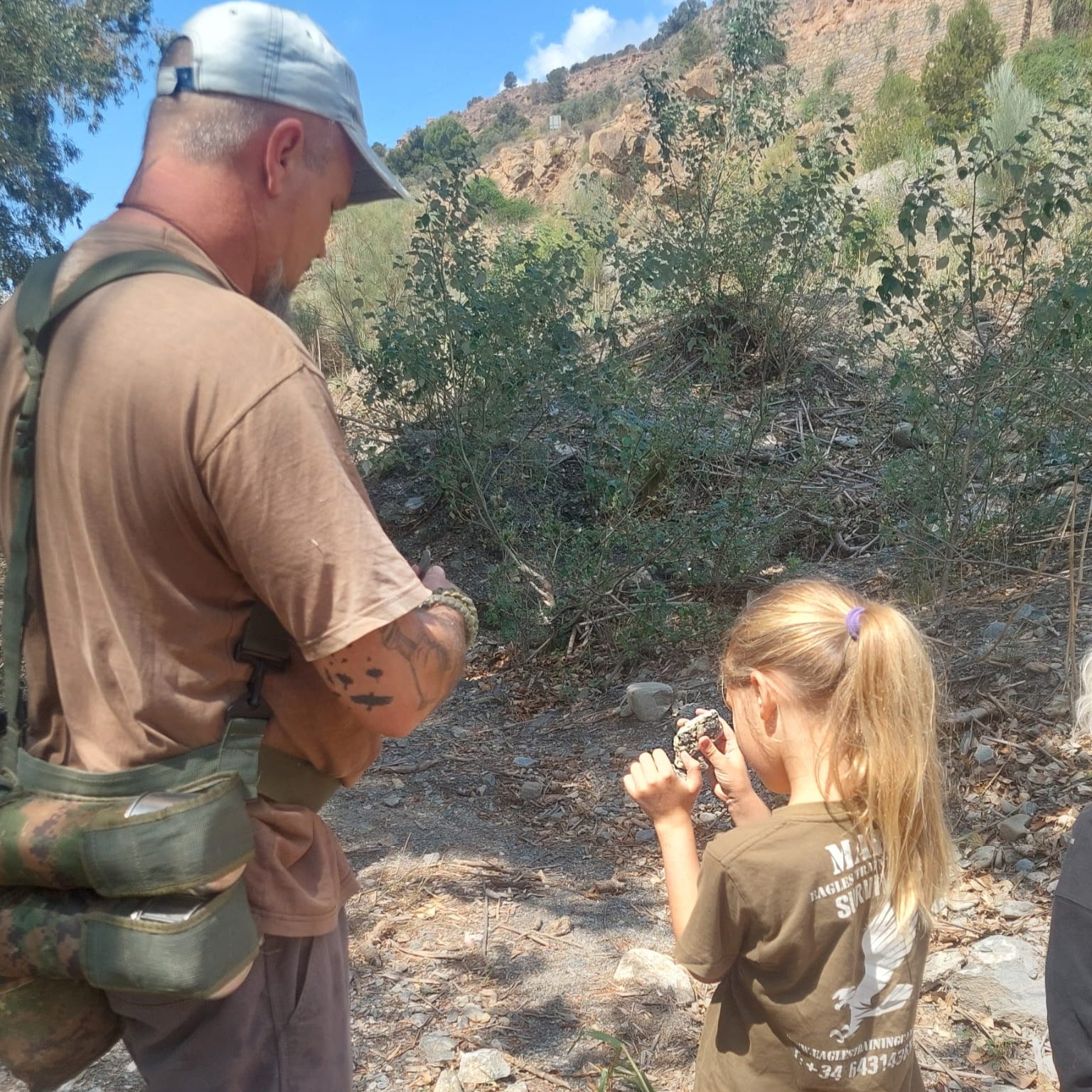 Man and young girl in a natural setting, possibly on a hike or outdoor adventure.